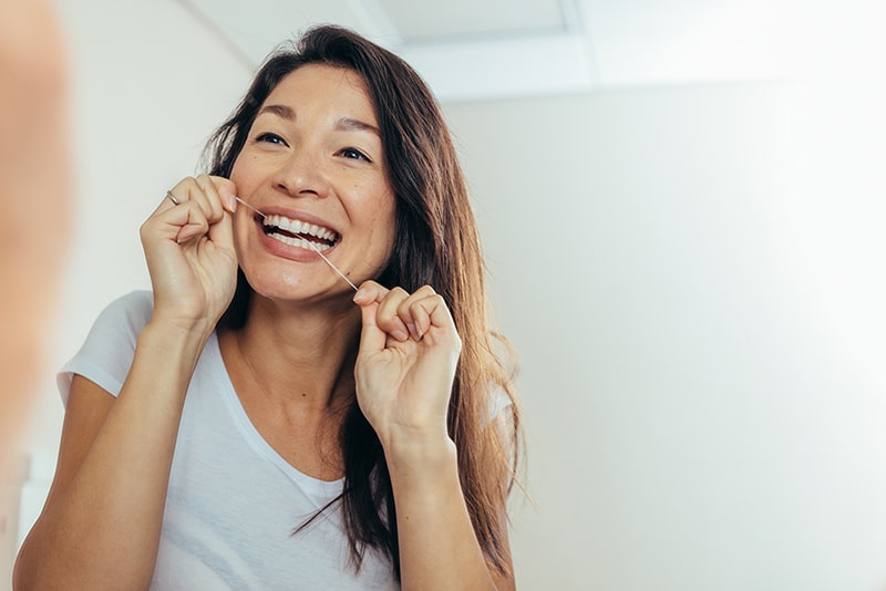 Reflection of woman using dental floss Root canals