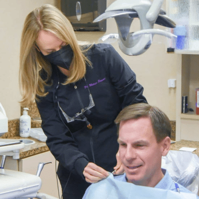 Discover cosmetic dentistry at stewart dental group 3 Man at the dentist for cosmetic dentistry procedure with dentist standing over him